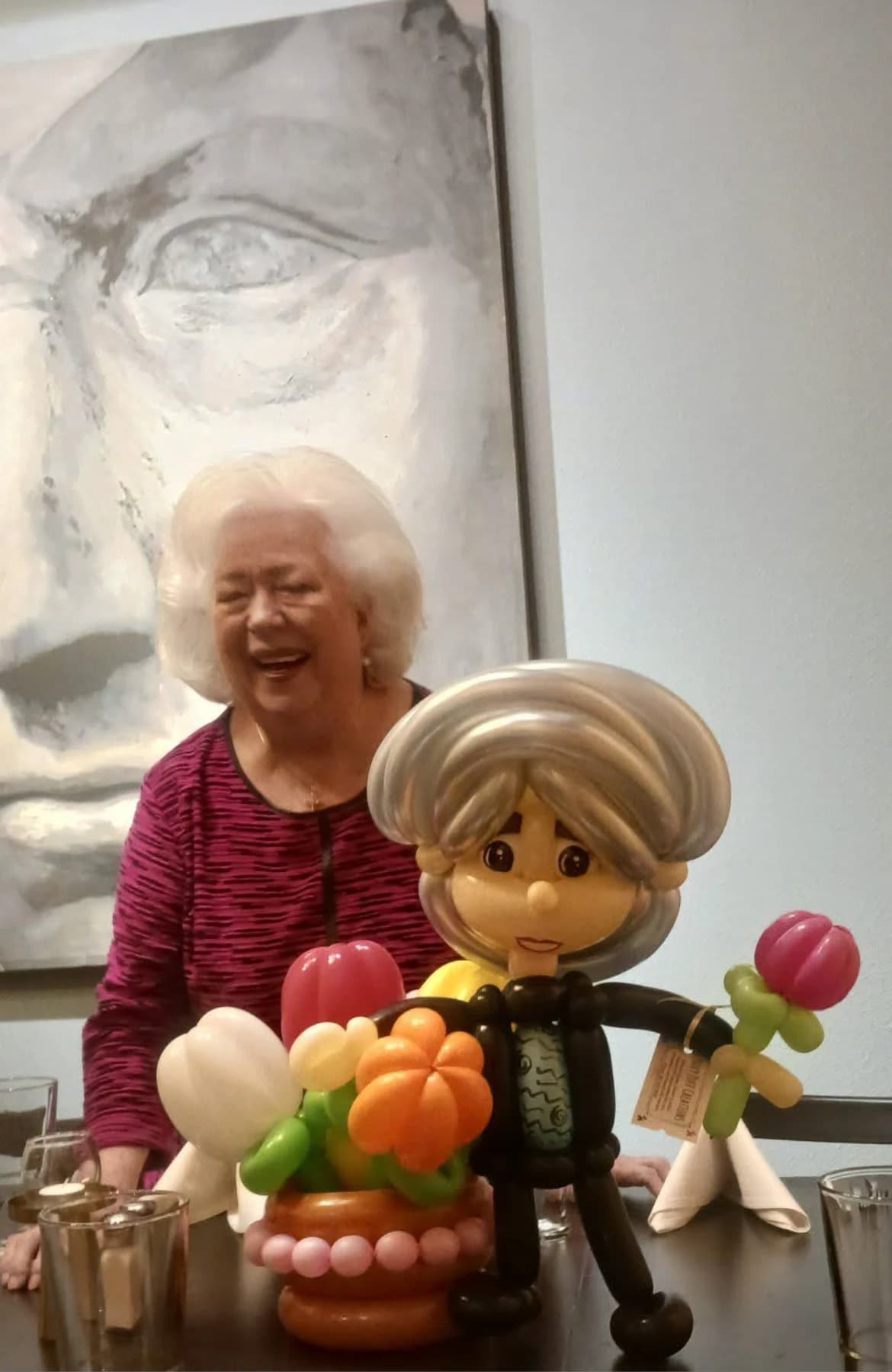 Smiling guest beside her personalized balloon caricature and flowers